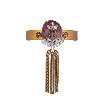 alt= "Statement bohemian gold cuff with magenta agate crystal and metal tassel detailing"
